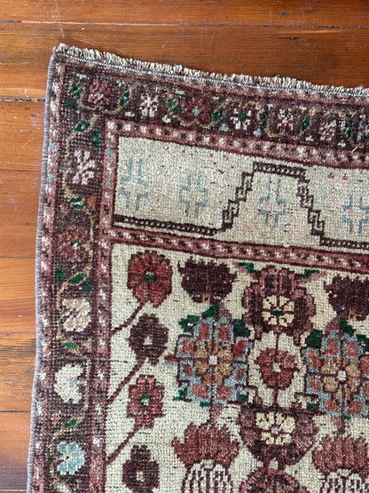 Vintage Turkish wool rug with a floral tree of life design in burgundy, green, and ivory tones, featuring a detailed border of small floral motifs.