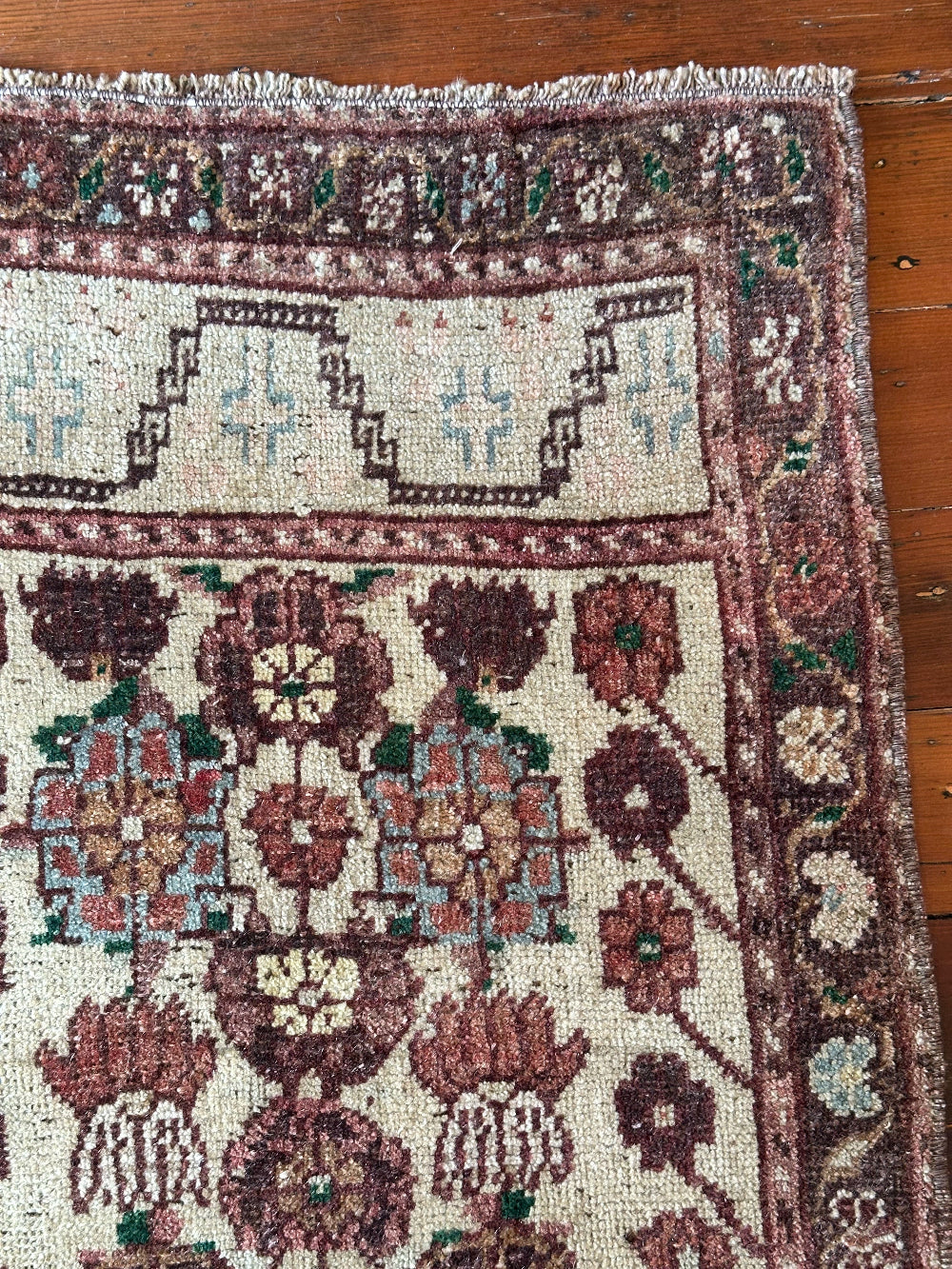Vintage Turkish wool rug with a floral tree of life design in burgundy, green, and ivory tones, featuring a detailed border of small floral motifs.