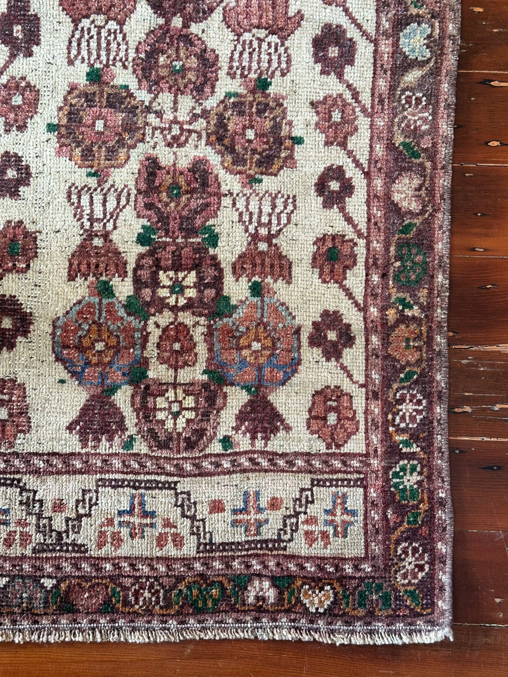 Vintage Turkish wool rug with a floral tree of life design in burgundy, green, and ivory tones, featuring a detailed border of small floral motifs.