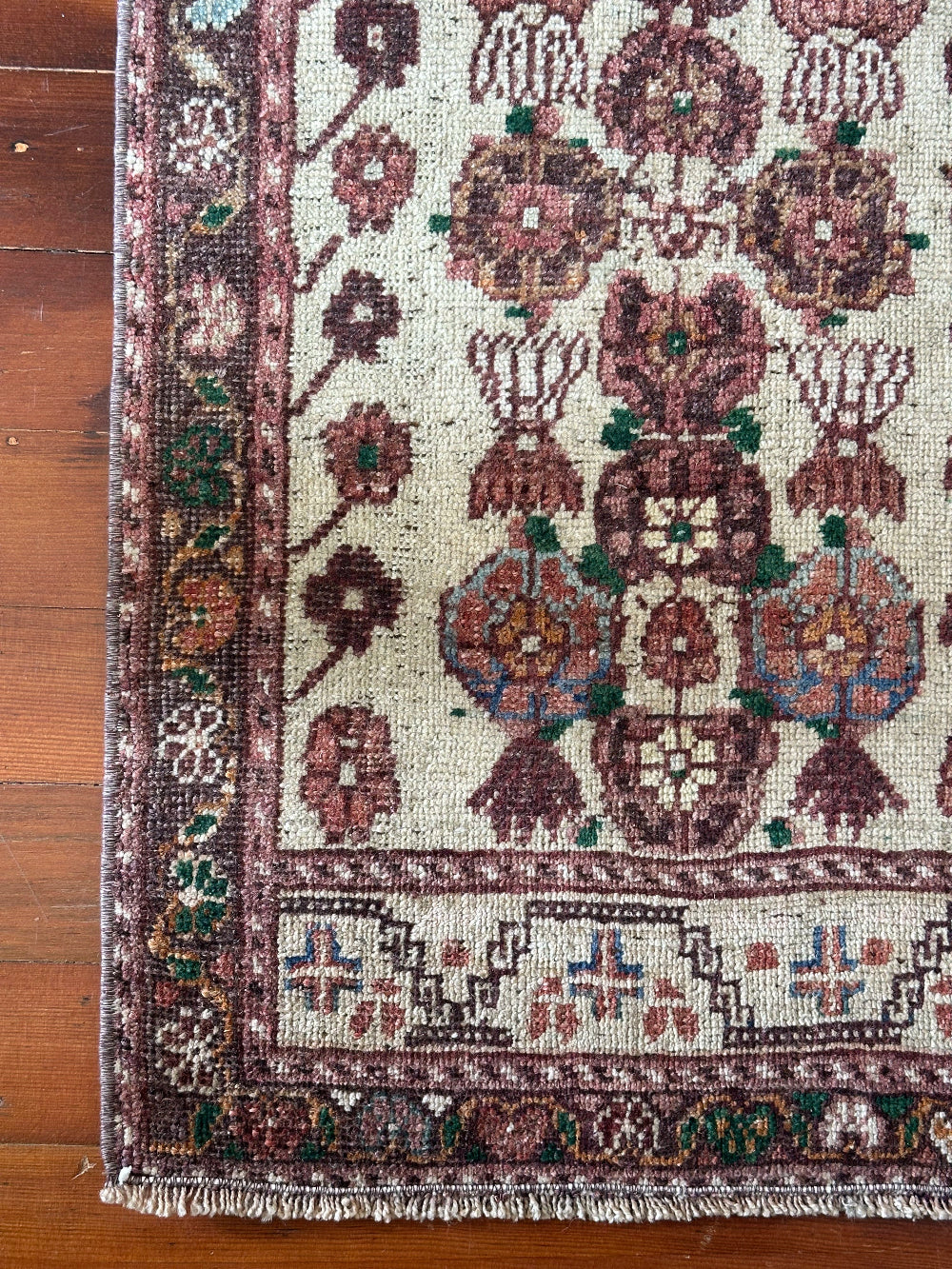Vintage Turkish wool rug with a floral tree of life design in burgundy, green, and ivory tones, featuring a detailed border of small floral motifs.