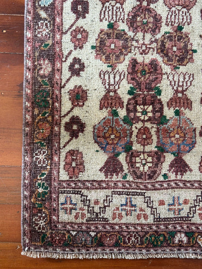 Vintage Turkish wool rug with a floral tree of life design in burgundy, green, and ivory tones, featuring a detailed border of small floral motifs.