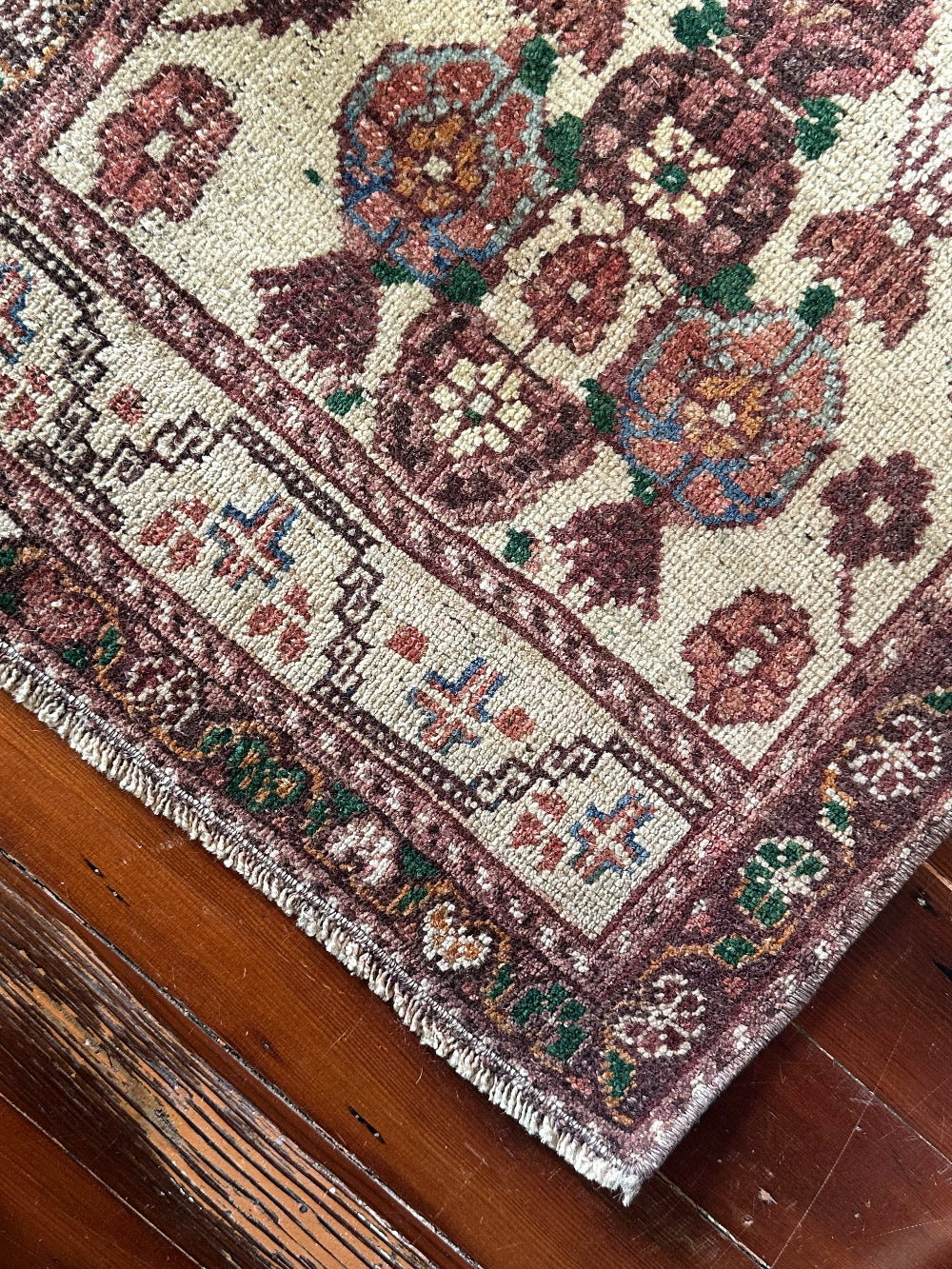 Vintage Turkish wool rug with a floral tree of life design in burgundy, green, and ivory tones, featuring a detailed border of small floral motifs.