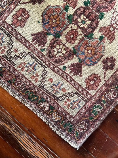 Vintage Turkish wool rug with a floral tree of life design in burgundy, green, and ivory tones, featuring a detailed border of small floral motifs.