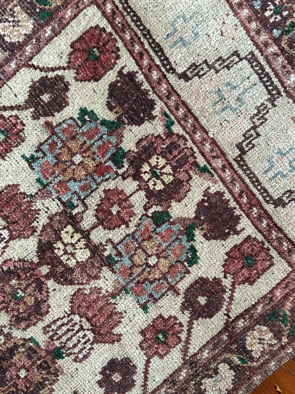 Vintage Turkish wool rug with a floral tree of life design in burgundy, green, and ivory tones, featuring a detailed border of small floral motifs.