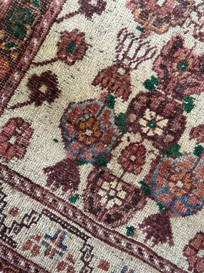 Vintage Turkish wool rug with a floral tree of life design in burgundy, green, and ivory tones, featuring a detailed border of small floral motifs.