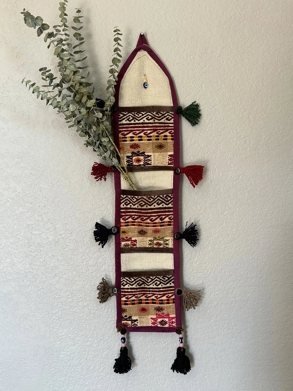 multi-colored three pocket wall organizer made from scraps of colorful Turkish kilim rugs with yarn tassels at each end