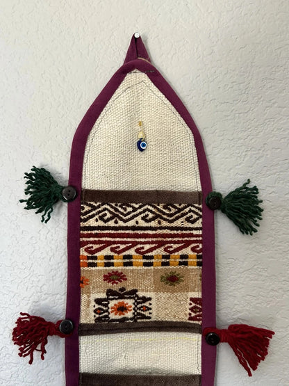 multi-colored three pocket wall organizer made from scraps of colorful Turkish kilim rugs with yarn tassels at each end