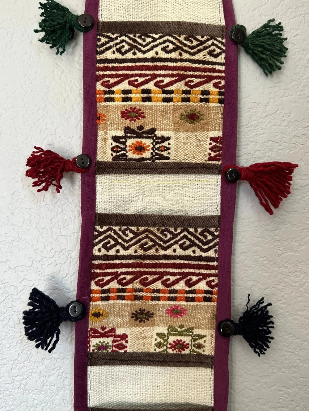 multi-colored three pocket wall organizer made from scraps of colorful Turkish kilim rugs with yarn tassels at each end