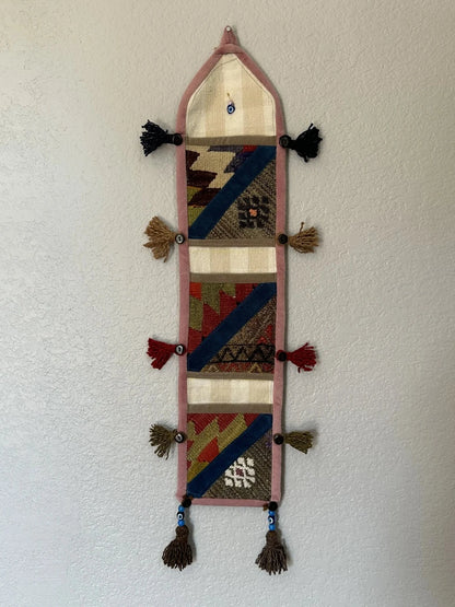 multi-colored three pocket wall organizer made from scraps of colorful Turkish kilim rugs with yarn tassels at each end