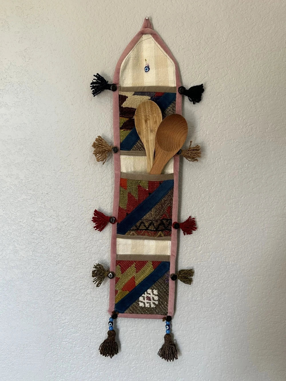 multi-colored three pocket wall organizer made from scraps of colorful Turkish kilim rugs with yarn tassels at each end