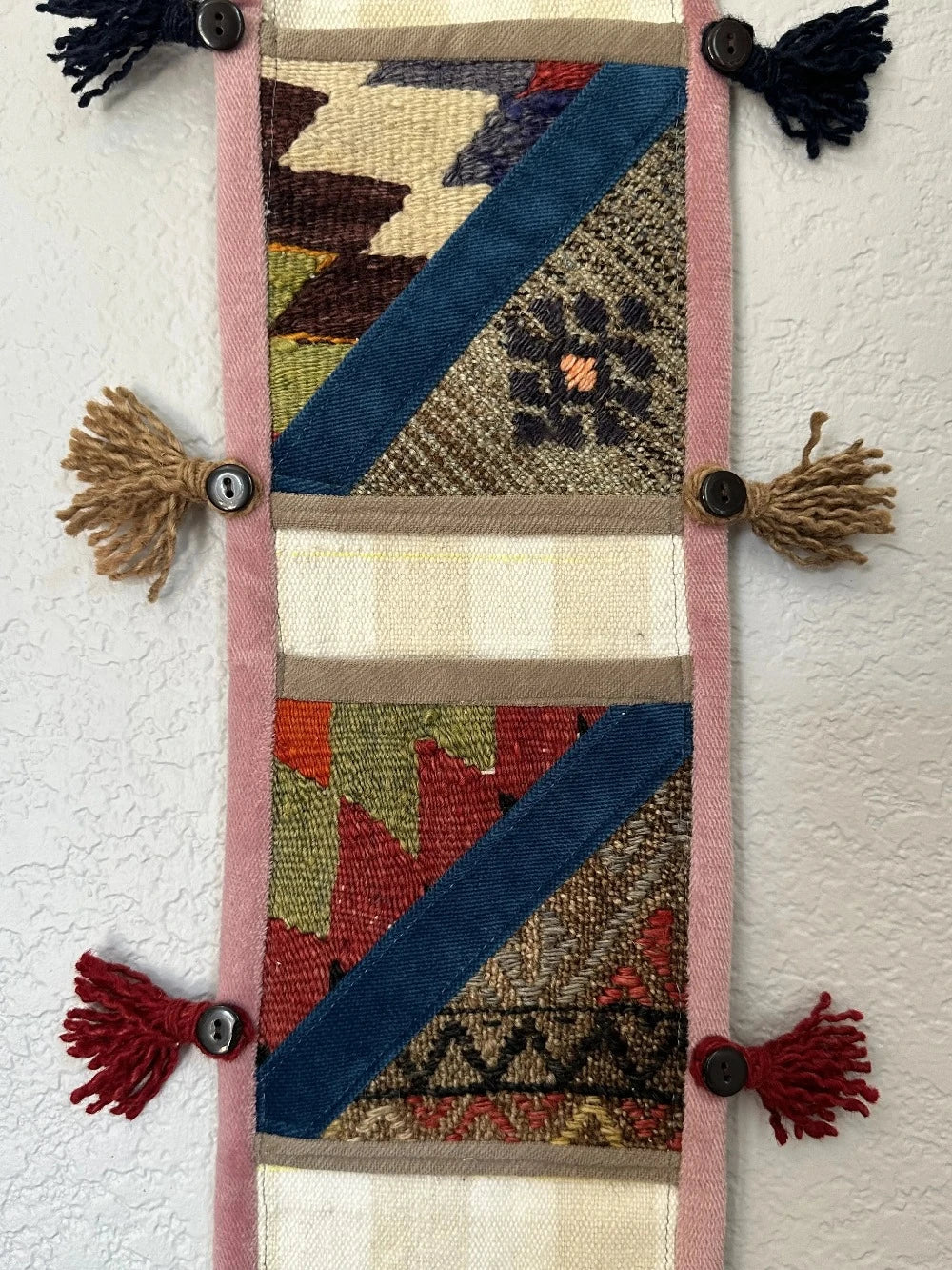 multi-colored three pocket wall organizer made from scraps of colorful Turkish kilim rugs with yarn tassels at each end