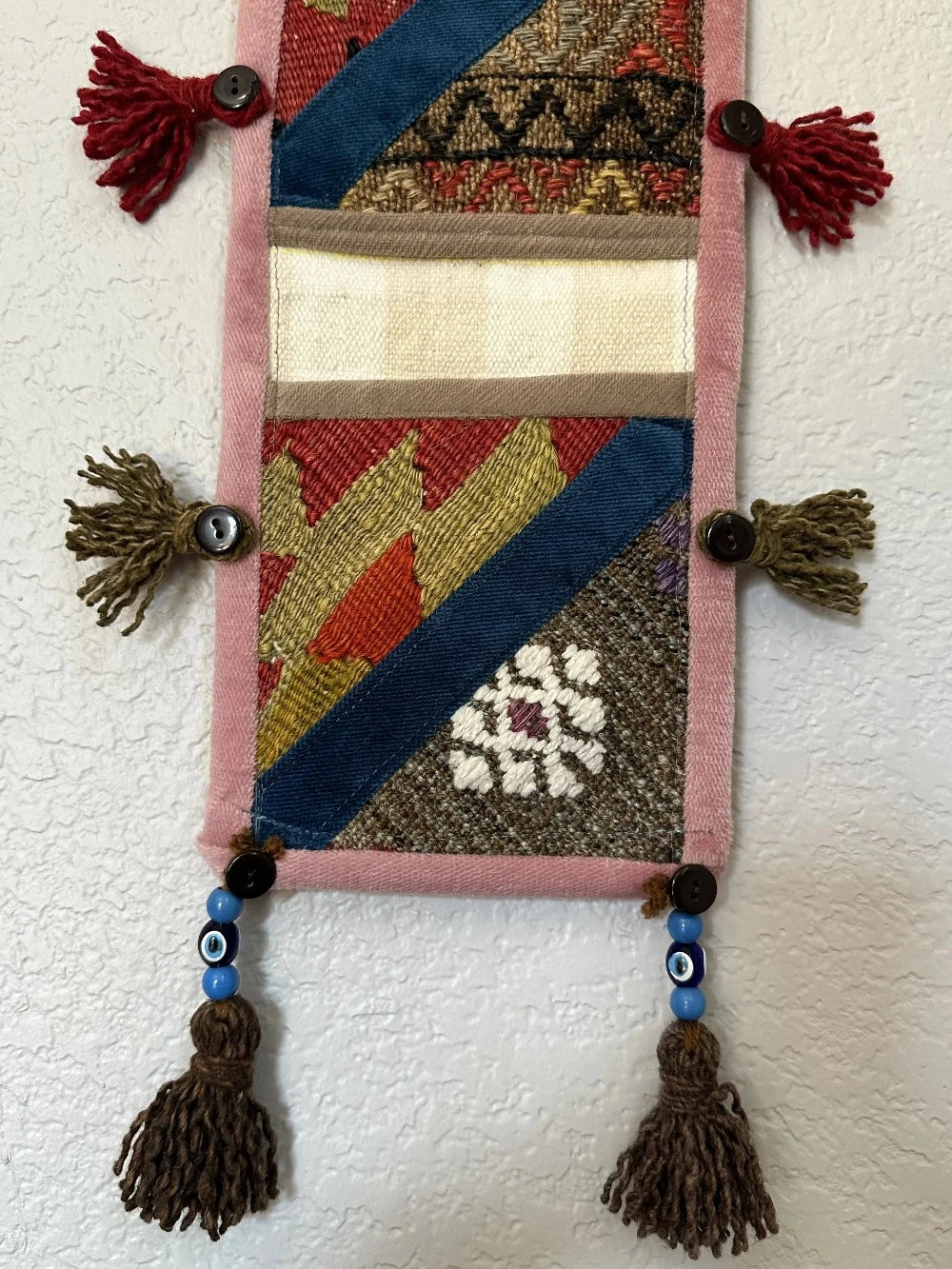 multi-colored three pocket wall organizer made from scraps of colorful Turkish kilim rugs with yarn tassels at each end