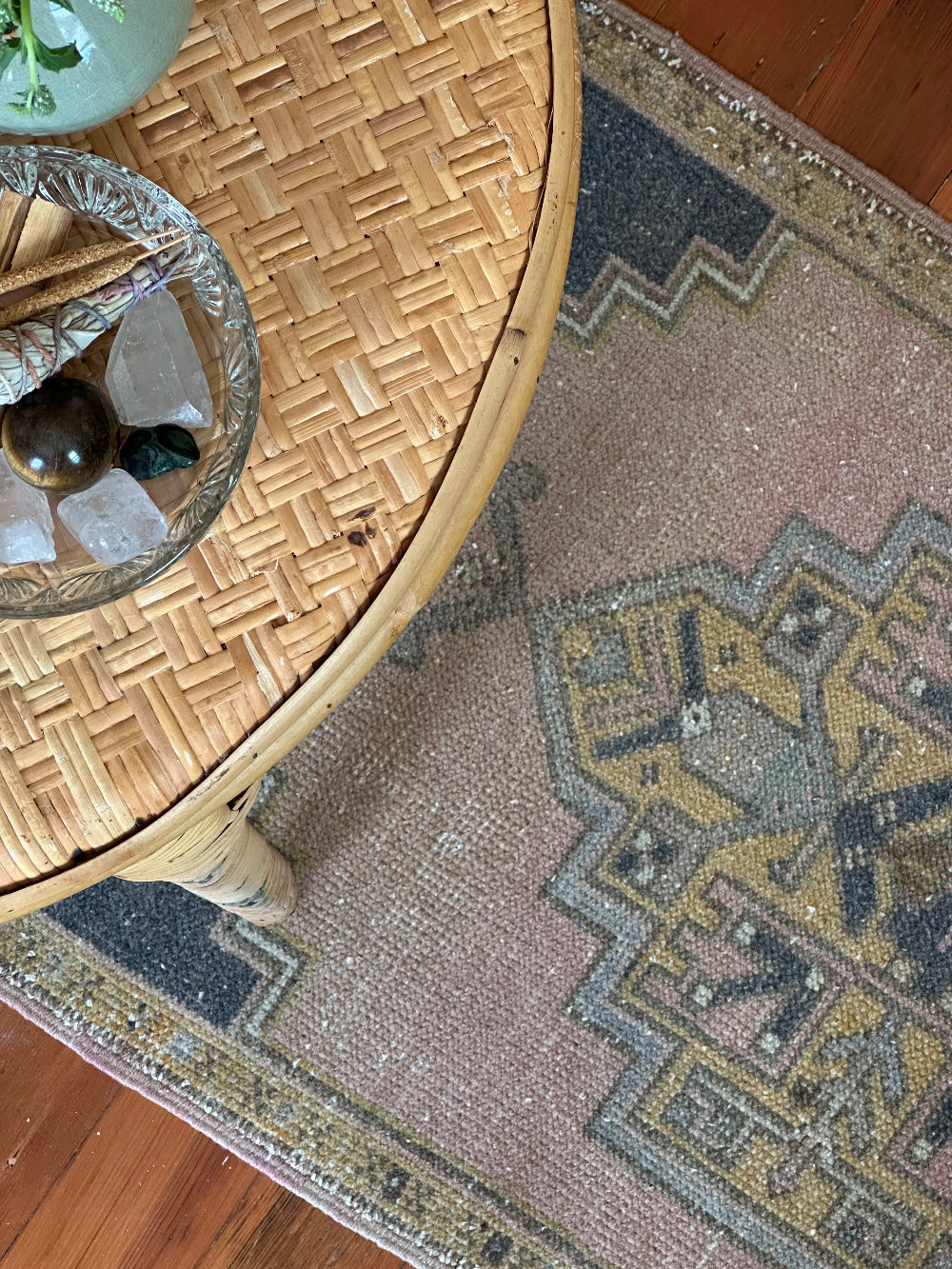 Vintage Turkish wool rug with a central geometric medallion in muted pink, gold, and dark charcoal tones, featuring stepped corner motifs and a distressed finish.