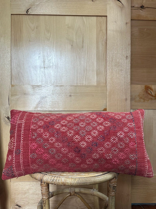 Rectangular red vintage Turkish kilim pillow with small repeating geometric patterns, made from handwoven wool.
