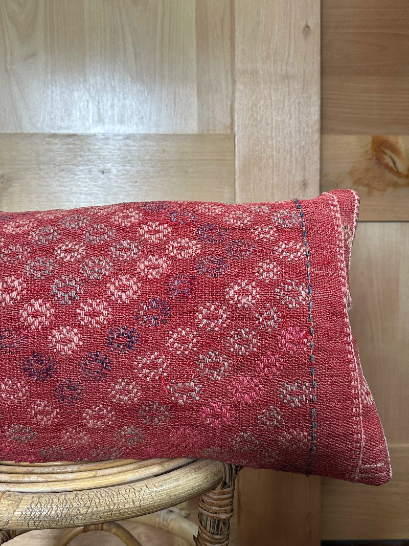 Rectangular red vintage Turkish kilim pillow with small repeating geometric patterns, made from handwoven wool.