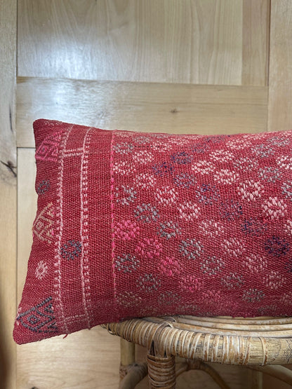 Rectangular red vintage Turkish kilim pillow with small repeating geometric patterns, made from handwoven wool.