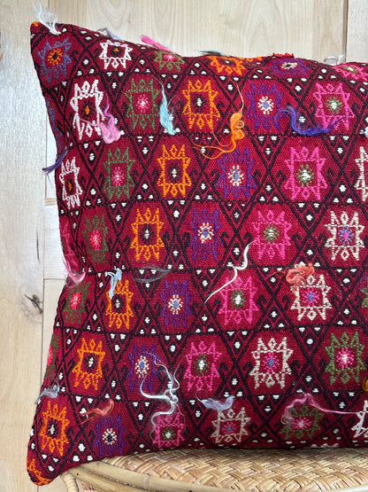 Bold handcrafted kilim pillow with intricate Berber-inspired embroidery. Made from repurposed vintage textiles in deep red, magenta, and orange hues with textured fringe details.