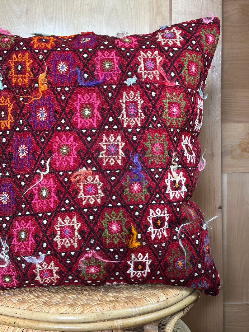 Bold handcrafted kilim pillow with intricate Berber-inspired embroidery. Made from repurposed vintage textiles in deep red, magenta, and orange hues with textured fringe details.