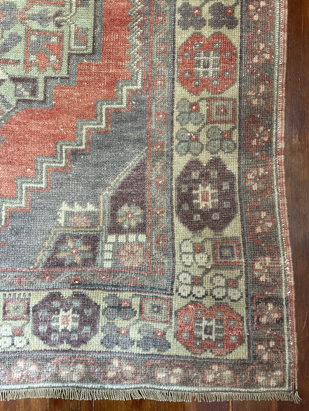 Vintage Turkish handwoven wool rug featuring a double medallion design in muted red, blue, and sage green tones with a detailed floral border.