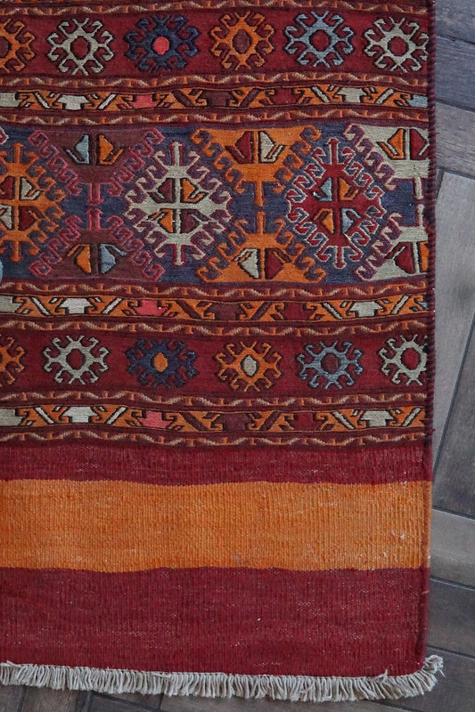 5 by 3 red and orange Turkish area rug featuring a striped pattern on the outside edges and a central striped pattern with geometric shapes and embroidery
