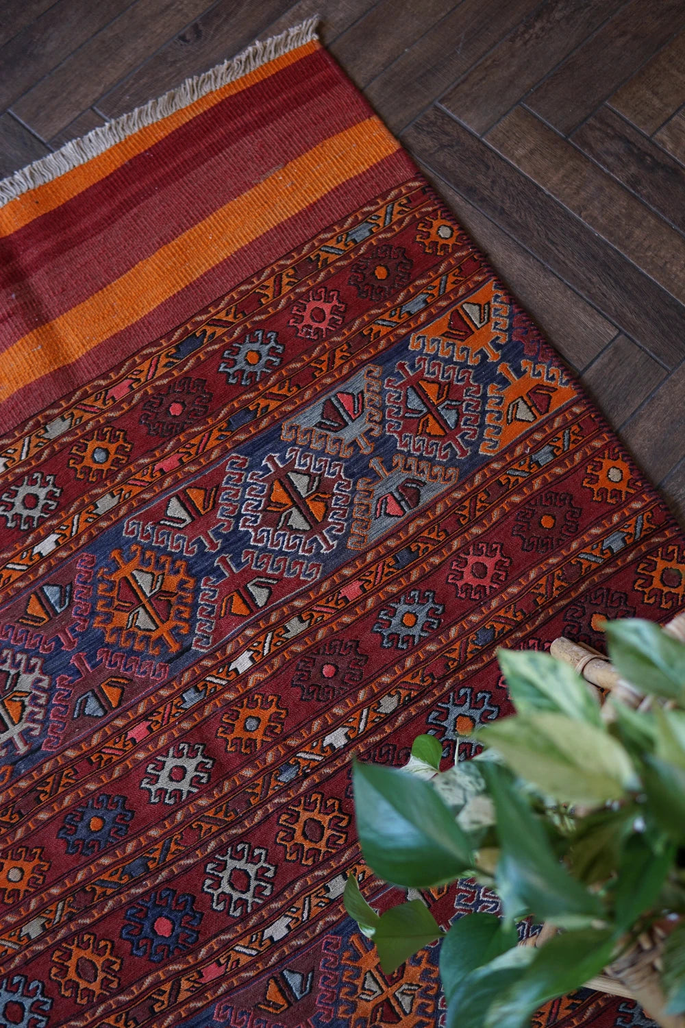 5 by 3 red and orange Turkish area rug featuring a striped pattern on the outside edges and a central striped pattern with geometric shapes and embroidery