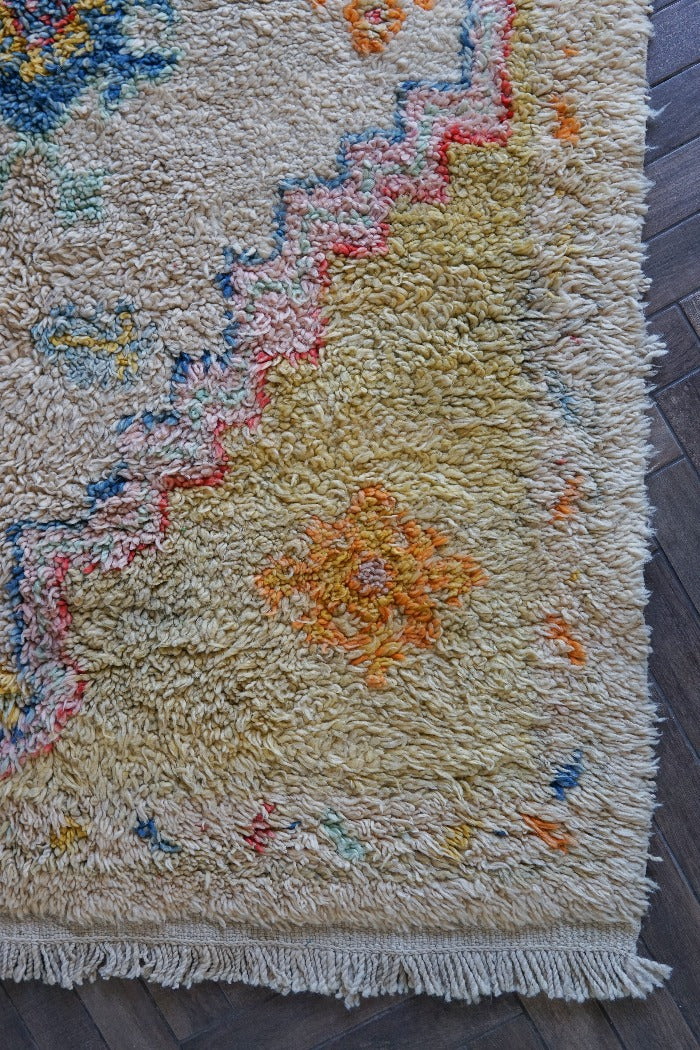 Large high pile Turkish area rug measuring 8 by 5, very muted yellow and cream coloring with pops of blue and orange, perfect for a living room room or bedroom space, unique, one-of-a-kind
