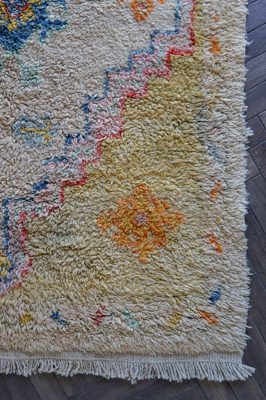 Large high pile Turkish area rug measuring 8 by 5, very muted yellow and cream coloring with pops of blue and orange, perfect for a living room room or bedroom space, unique, one-of-a-kind