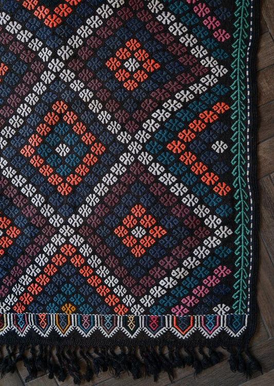 4.2 by 2.9 foot Turkish area rug or tapestry with goat hair fringe, featuring deep blues and blacks and bright pops of orange and white diamond patterns