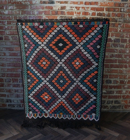 4.2 by 2.9 foot Turkish area rug or tapestry with goat hair fringe, featuring deep blues and blacks and bright pops of orange and white diamond patterns