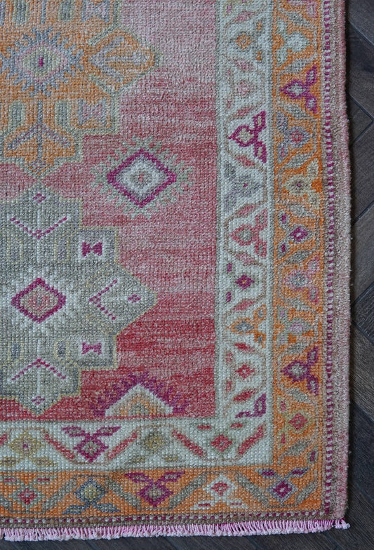 12 feet by 3 ft pink Turkish runner with beautiful large medallions down the center and pops of orange, sand, and dark pink throughout.