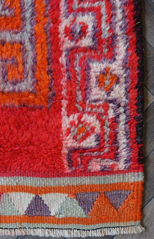 11 foot by 3 foot Herki Turkish runner with beautiful deep red pile as the main color, border on each side with triangles in orange, purple, light blue and cream and large medallions in the center