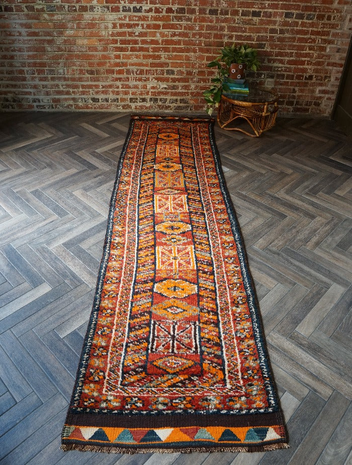 11 foot by 3 foot Turkish high pile Herki runner, featuring a black, red and orange geometric pattern throughout