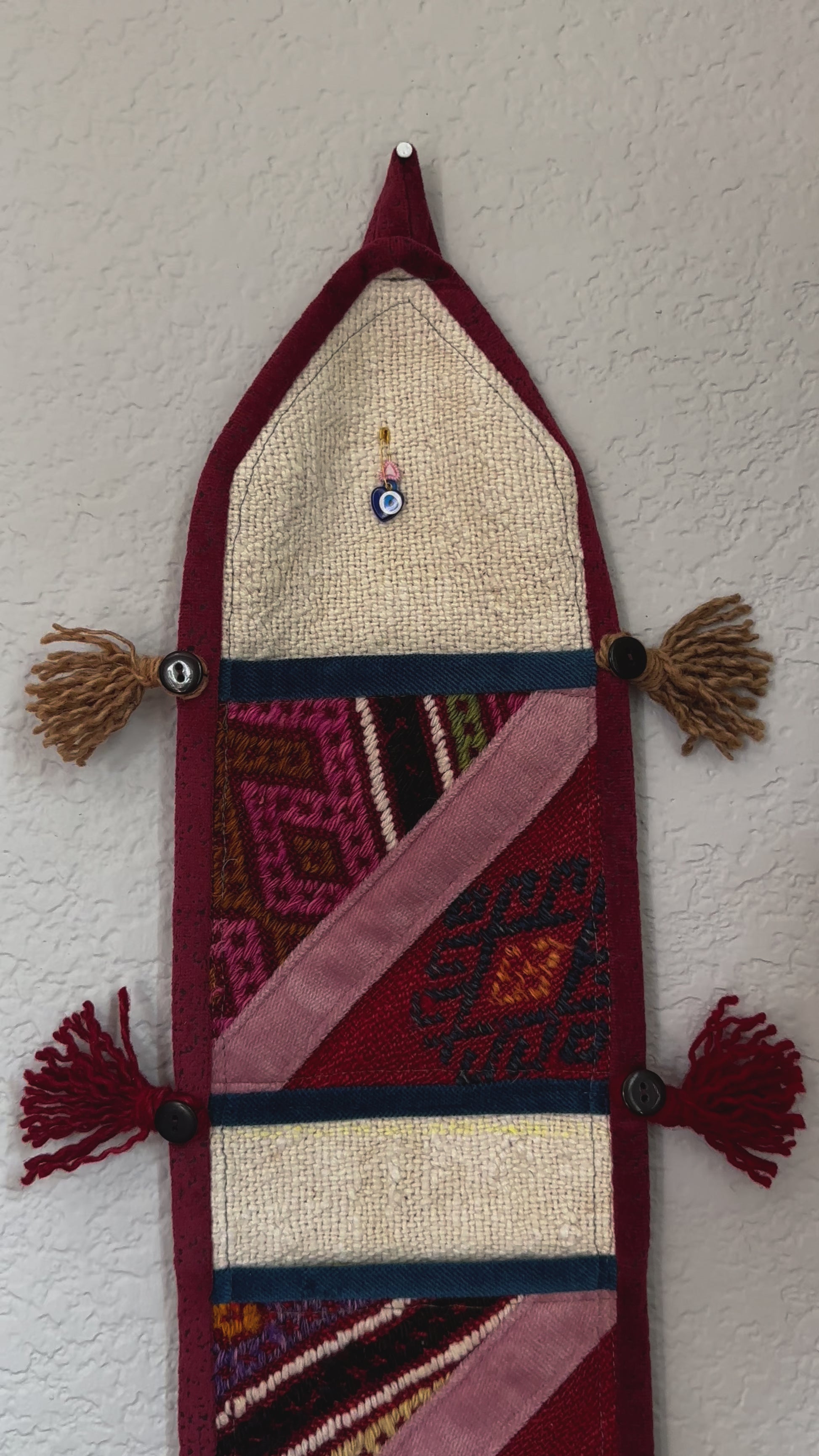 multi-colored three pocket wall organizer made from scraps of colorful Turkish kilim rugs with yarn tassels at each end