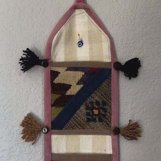 multi-colored three pocket wall organizer made from scraps of colorful Turkish kilim rugs with yarn tassels at each end