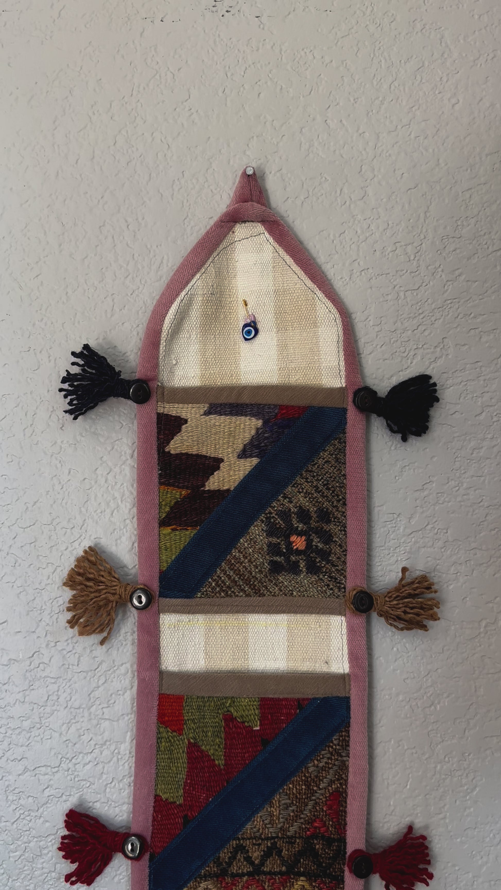 multi-colored three pocket wall organizer made from scraps of colorful Turkish kilim rugs with yarn tassels at each end