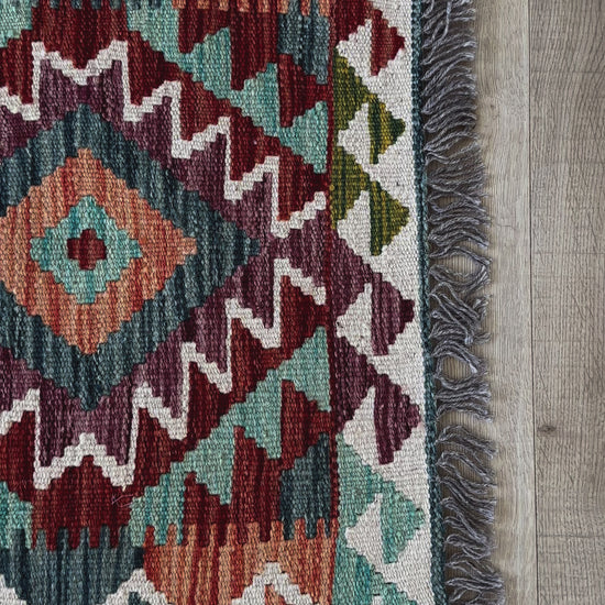 mini colorful Turkish rug featuring pops of red, orange green and blue and geometric diamond pattern throughout