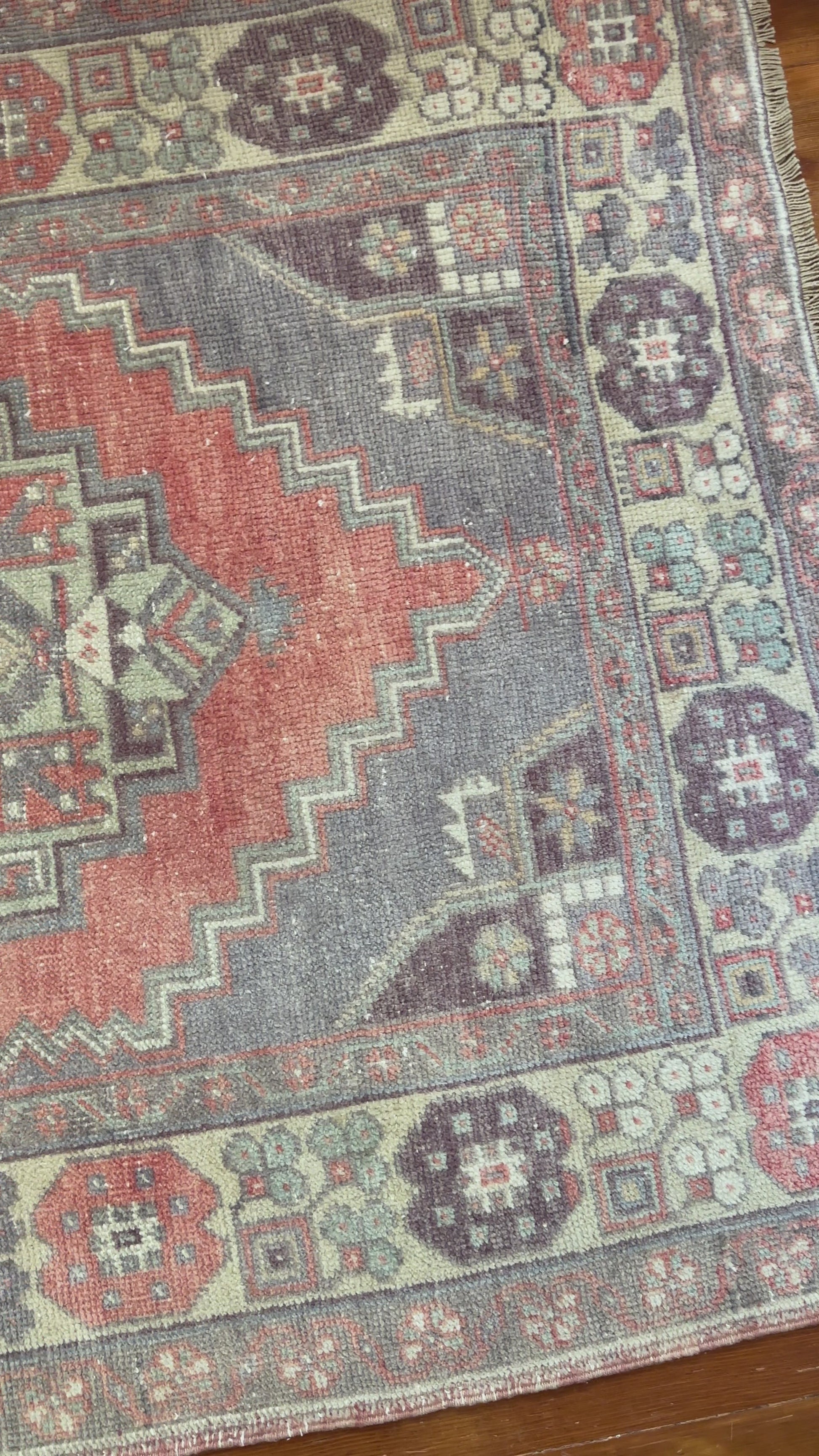 Vintage Turkish handwoven wool rug featuring a double medallion design in muted red, blue, and sage green tones with a detailed floral border.