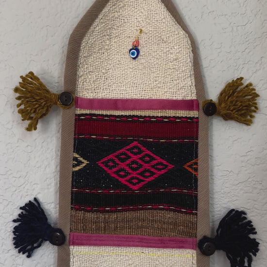 multi-colored three pocket wall organizer made from scraps of colorful Turkish kilim rugs with yarn tassels at each end