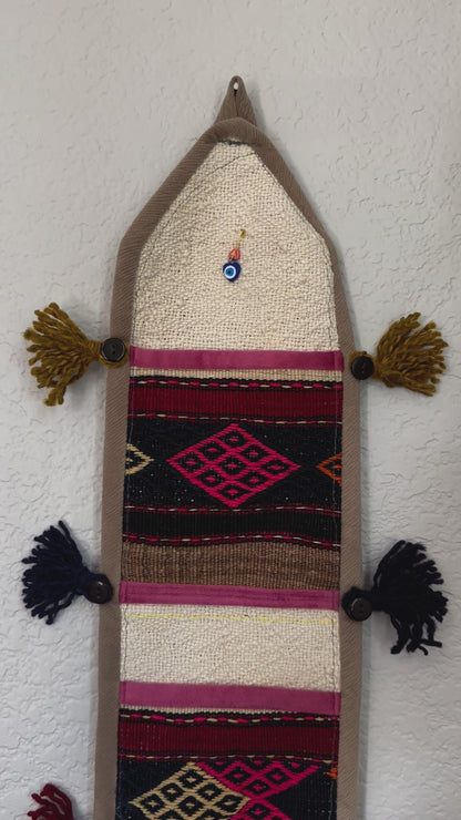 multi-colored three pocket wall organizer made from scraps of colorful Turkish kilim rugs with yarn tassels at each end