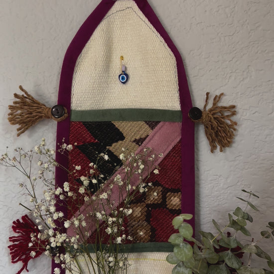 multi-colored three pocket wall organizer made from scraps of colorful Turkish kilim rugs with yarn tassels at each end