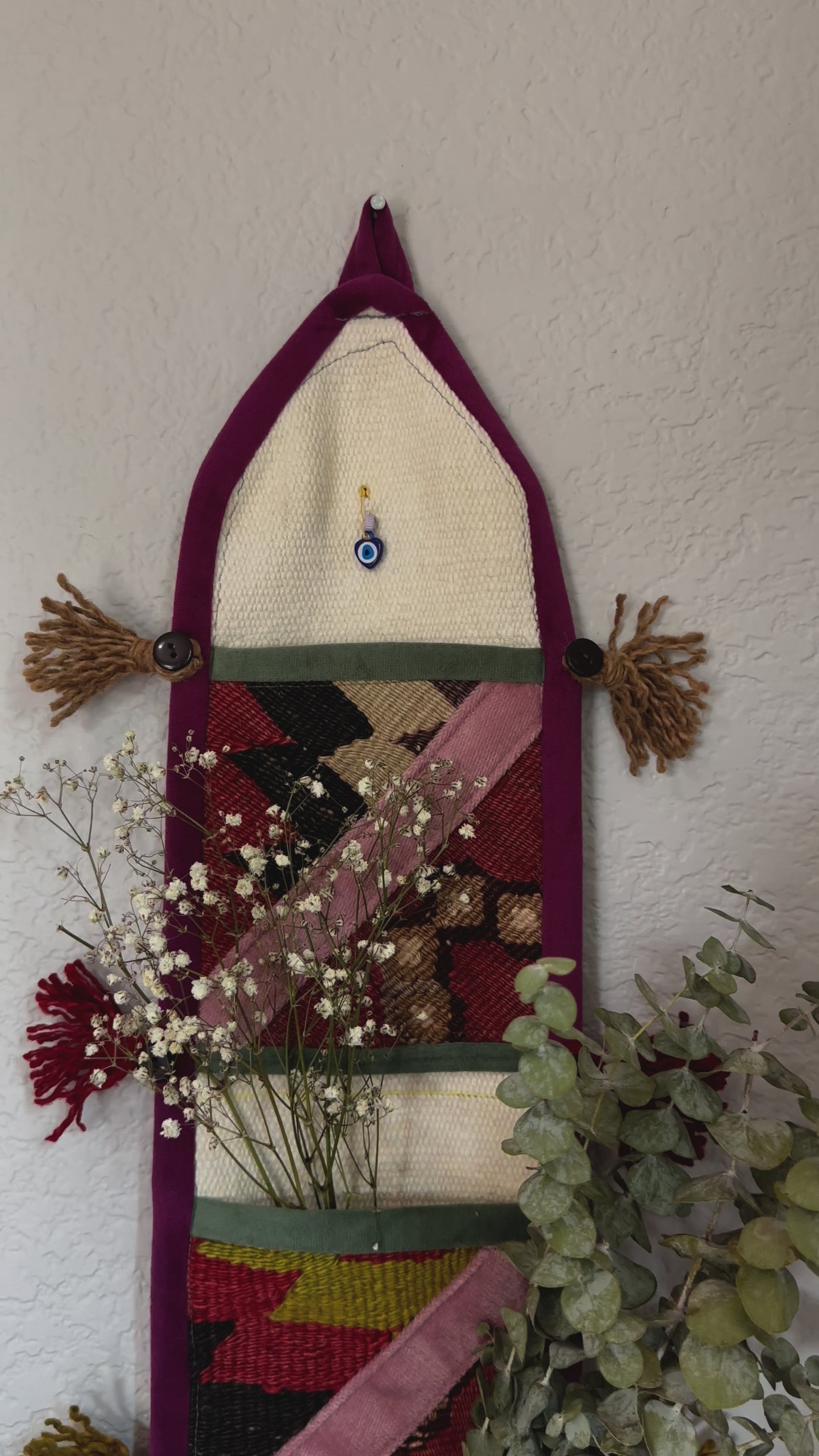 multi-colored three pocket wall organizer made from scraps of colorful Turkish kilim rugs with yarn tassels at each end