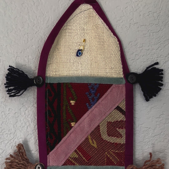 multi-colored three pocket wall organizer made from scraps of colorful Turkish kilim rugs with yarn tassels at each end