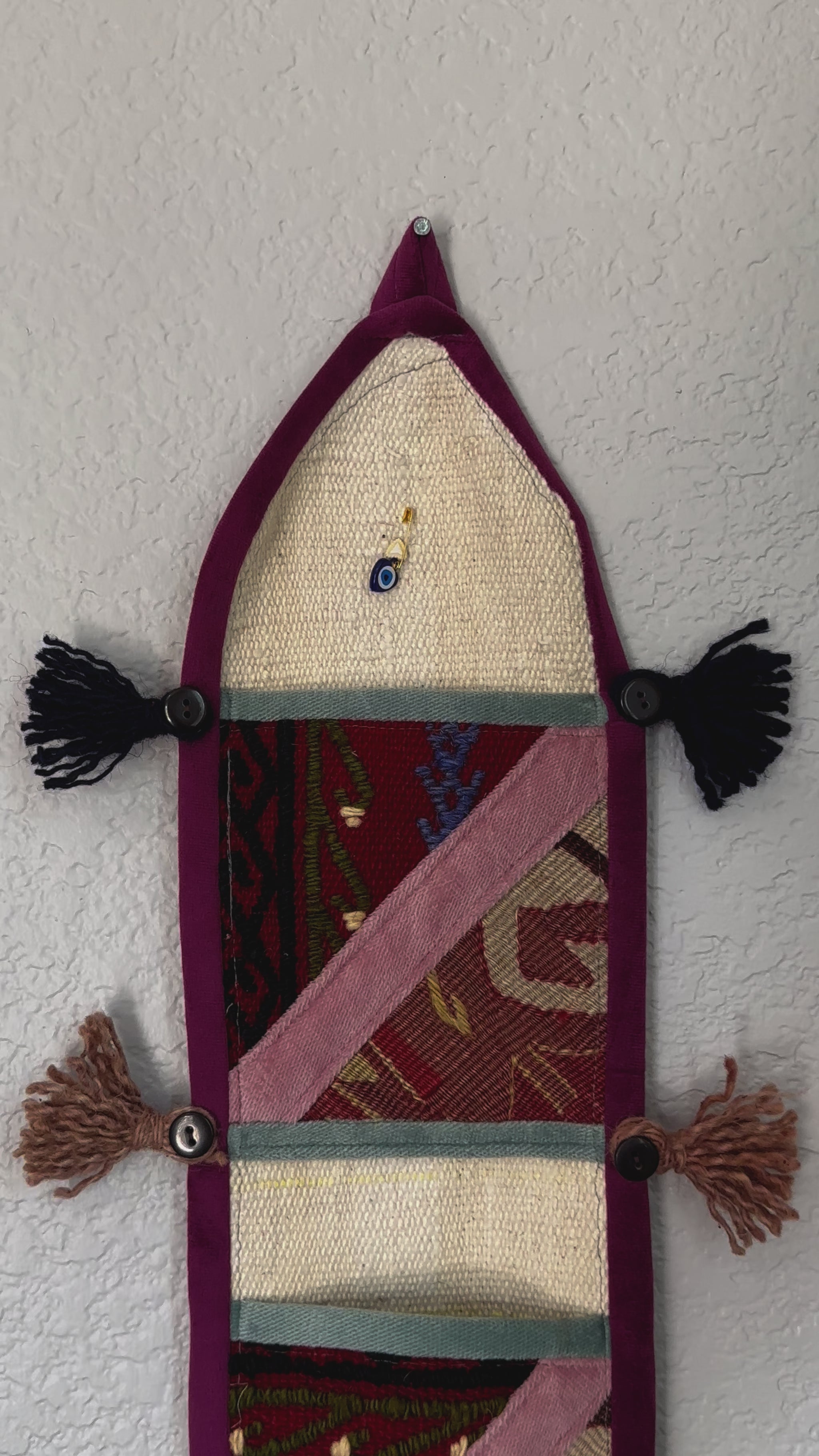 multi-colored three pocket wall organizer made from scraps of colorful Turkish kilim rugs with yarn tassels at each end