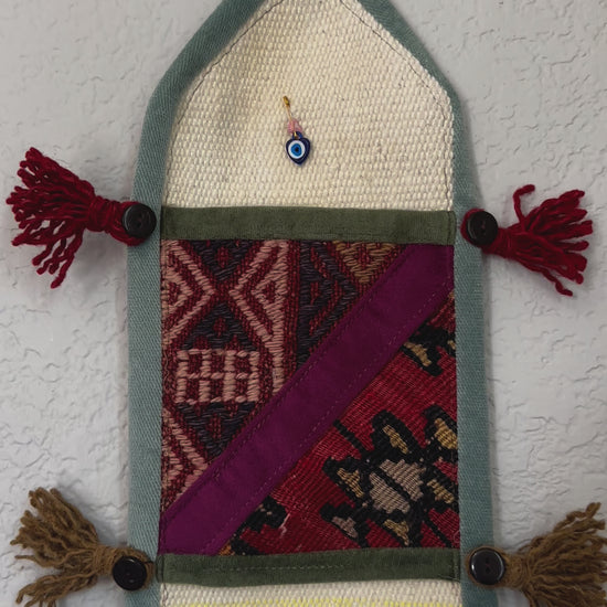 multi-colored three pocket wall organizer made from scraps of colorful Turkish kilim rugs with yarn tassels at each end