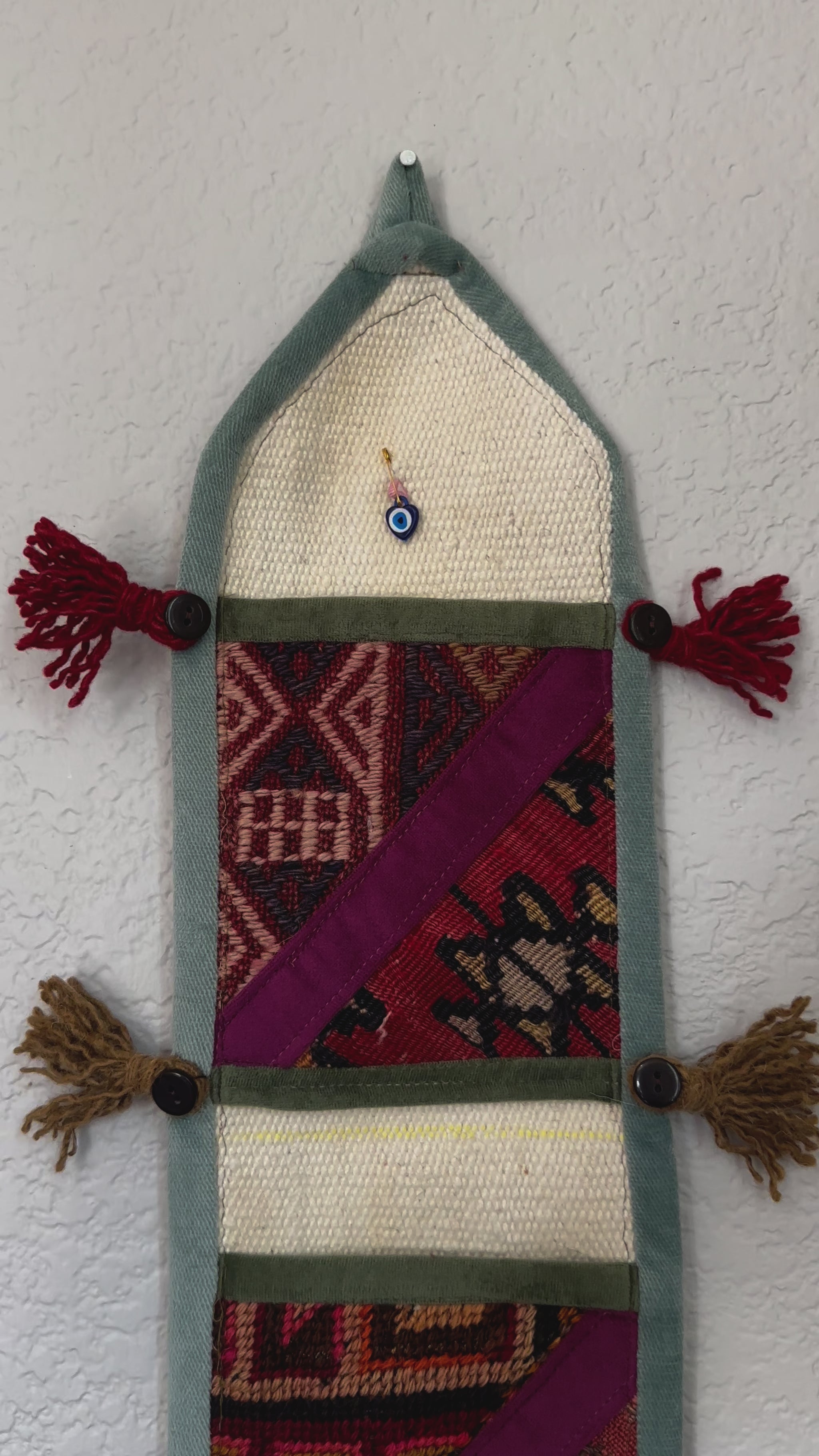 multi-colored three pocket wall organizer made from scraps of colorful Turkish kilim rugs with yarn tassels at each end