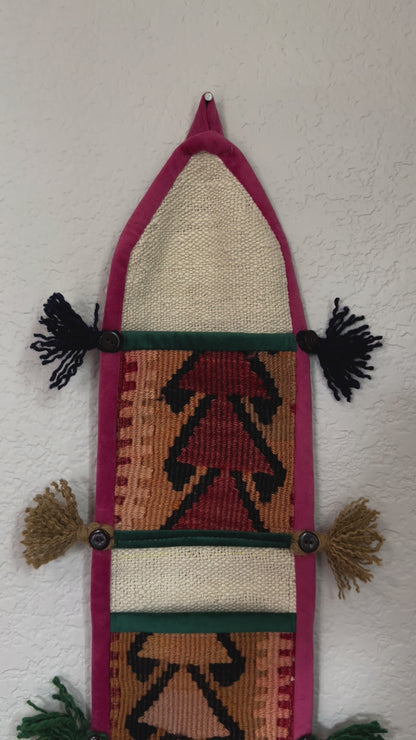 multi-colored three pocket wall organizer made from scraps of colorful Turkish kilim rugs with yarn tassels at each end