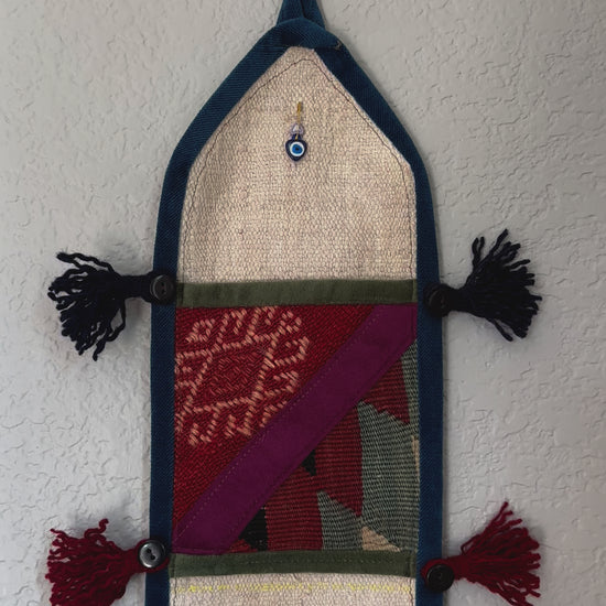 multi-colored three pocket wall organizer made from scraps of colorful Turkish kilim rugs with yarn tassels at each end