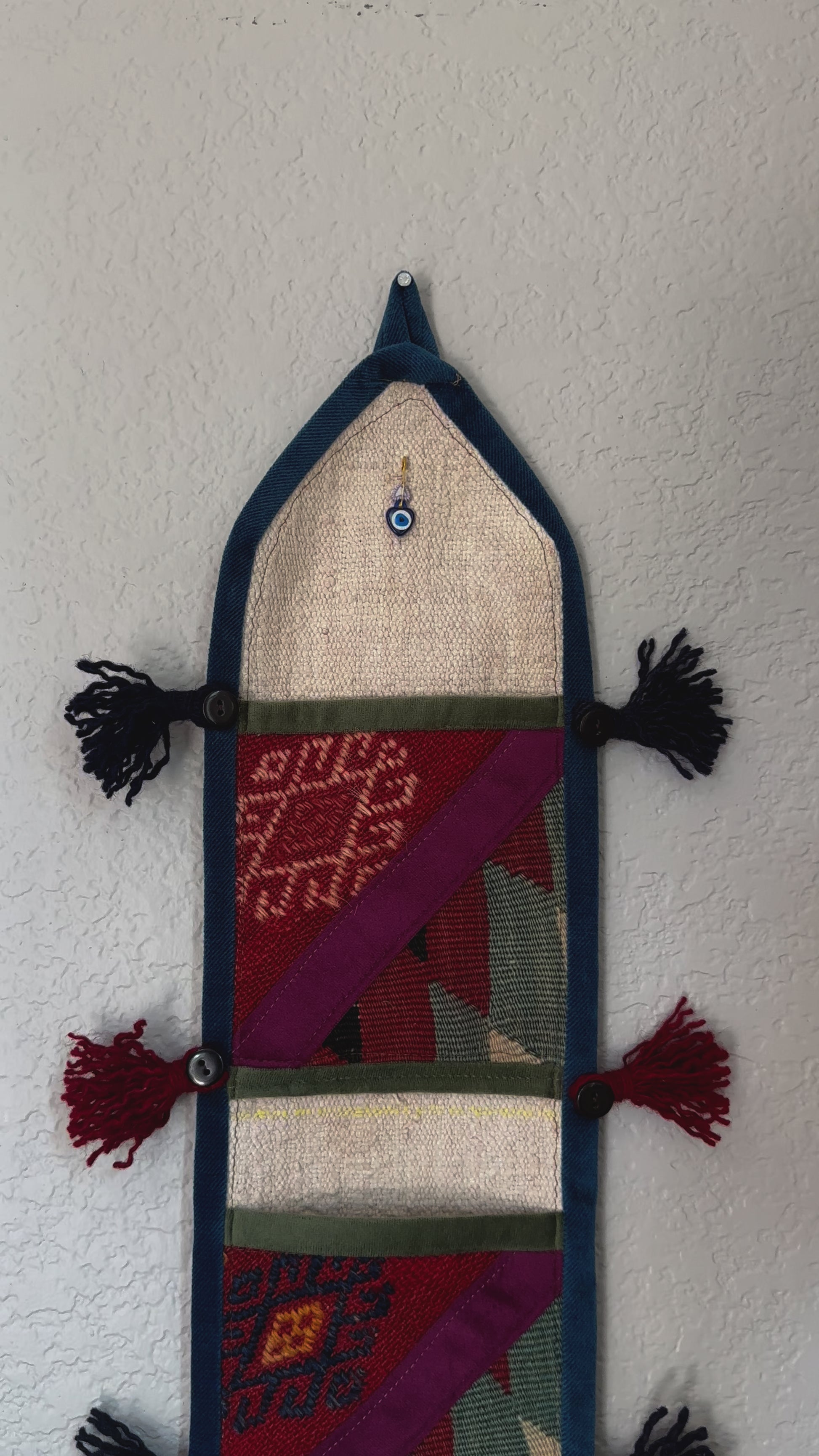 multi-colored three pocket wall organizer made from scraps of colorful Turkish kilim rugs with yarn tassels at each end