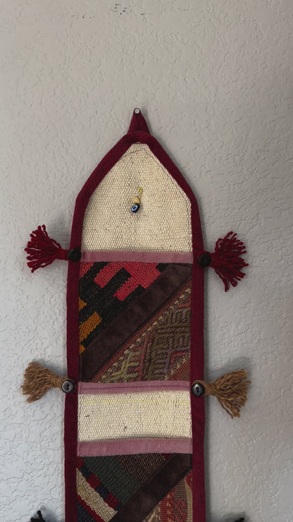 multi-colored three pocket wall organizer made from scraps of colorful Turkish kilim rugs with yarn tassels at each end