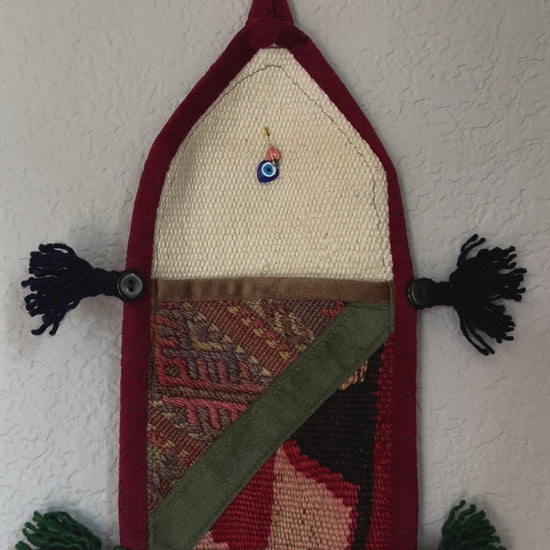 multi-colored three pocket wall organizer made from scraps of colorful Turkish kilim rugs with yarn tassels at each end